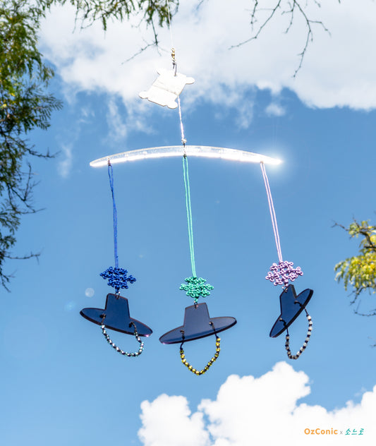 Decorative hanging mobile with colorful hats against a blue sky